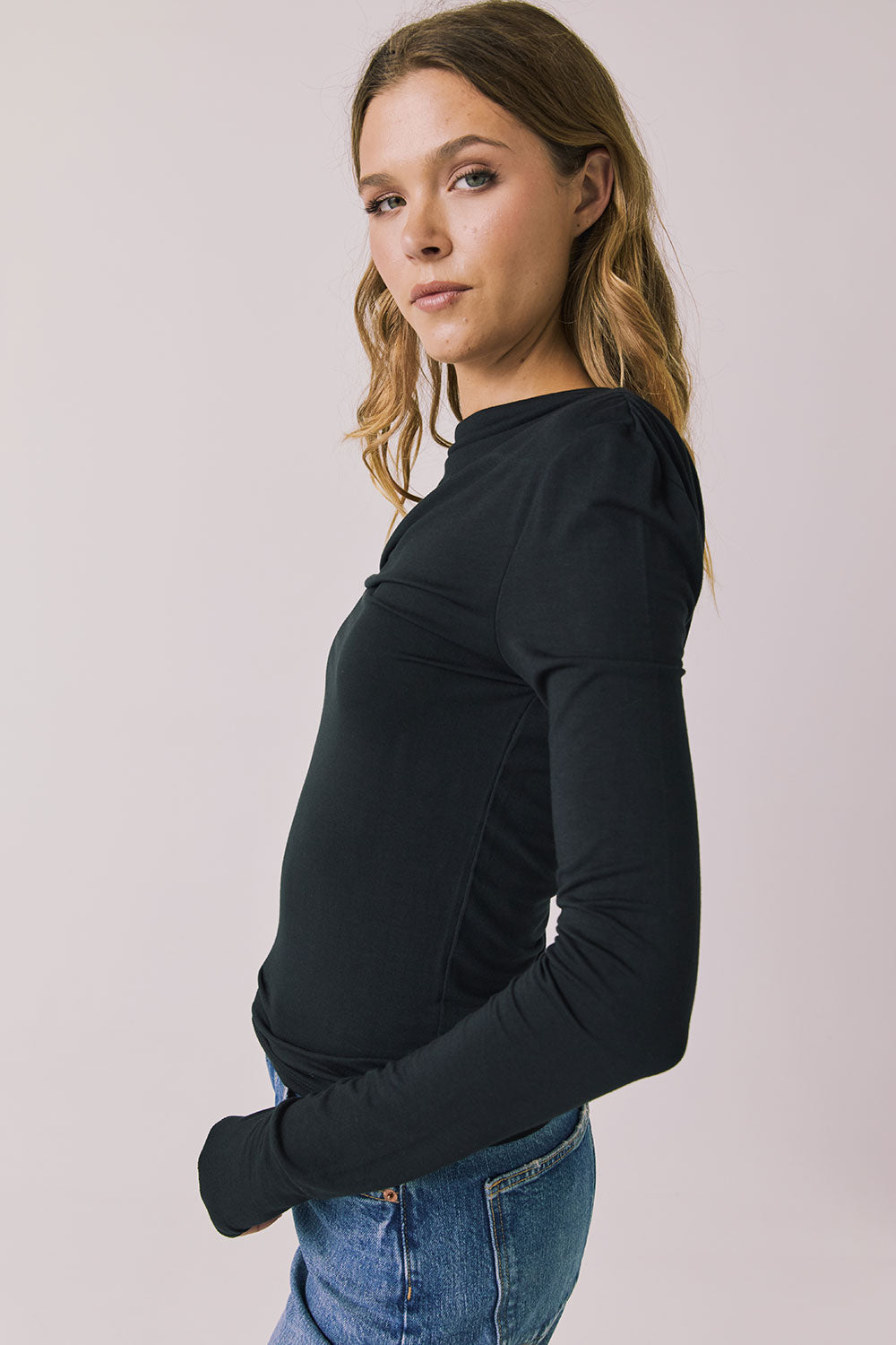 Side view of woman wearing Chaser’s Owen True Black Long Sleeve top showing soft drape and lightweight texture on a light gray background
