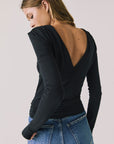 Back view of woman wearing Chaser’s Owen True Black Long Sleeve top featuring a low-cut open back design on a light gray background