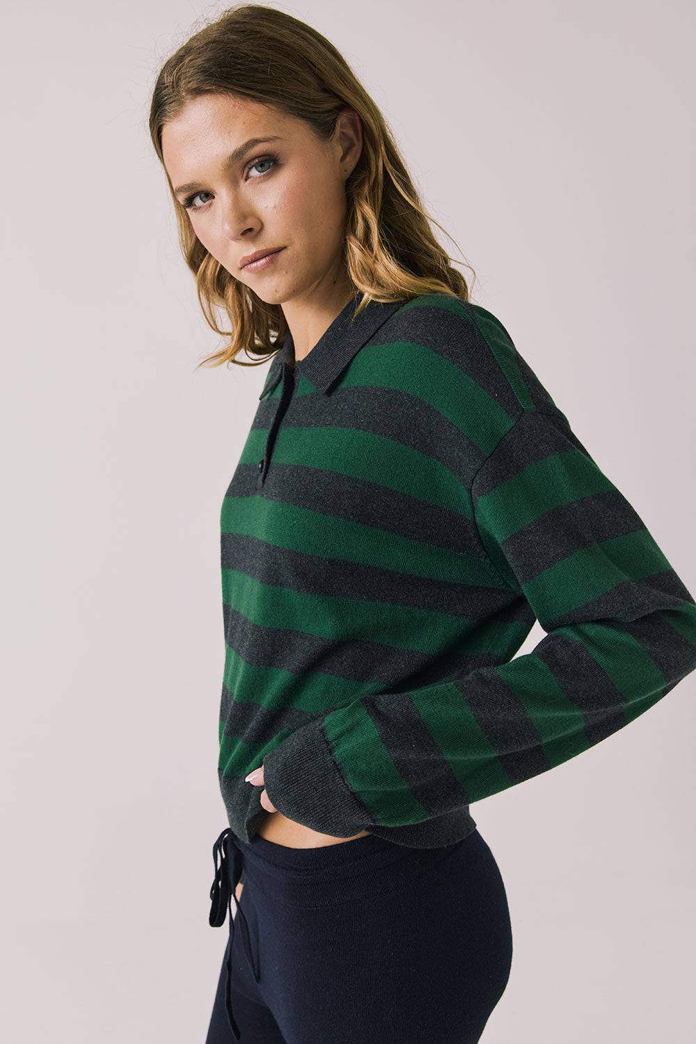 Side view of woman wearing Chaser’s Boyfriend Timeless Stripe Pullover with green and blue striped pattern on a plain background.