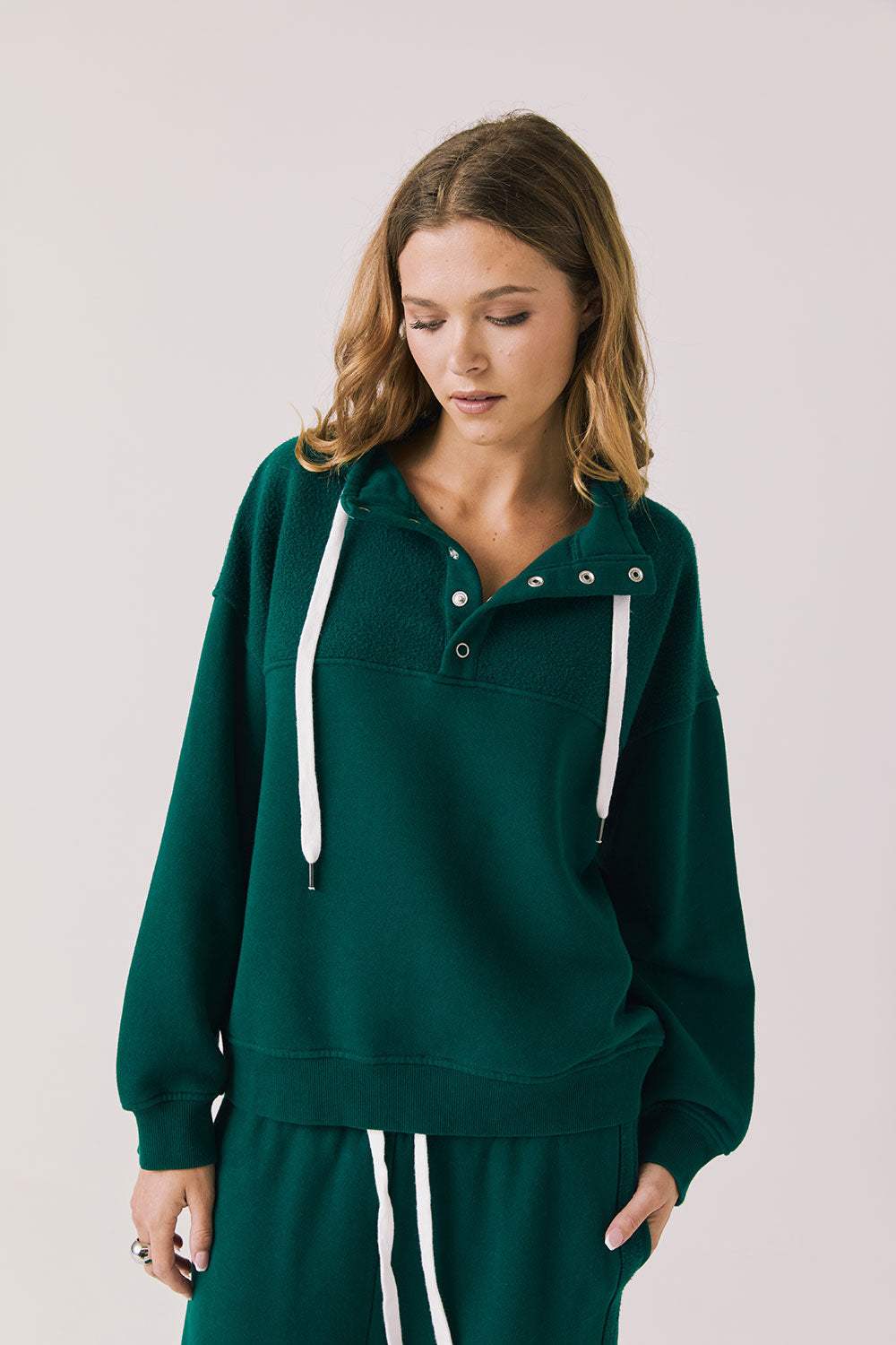 Front view of woman wearing Chaser’s City Blue Grass Green Half Zip Pullover with white drawstrings on a plain background