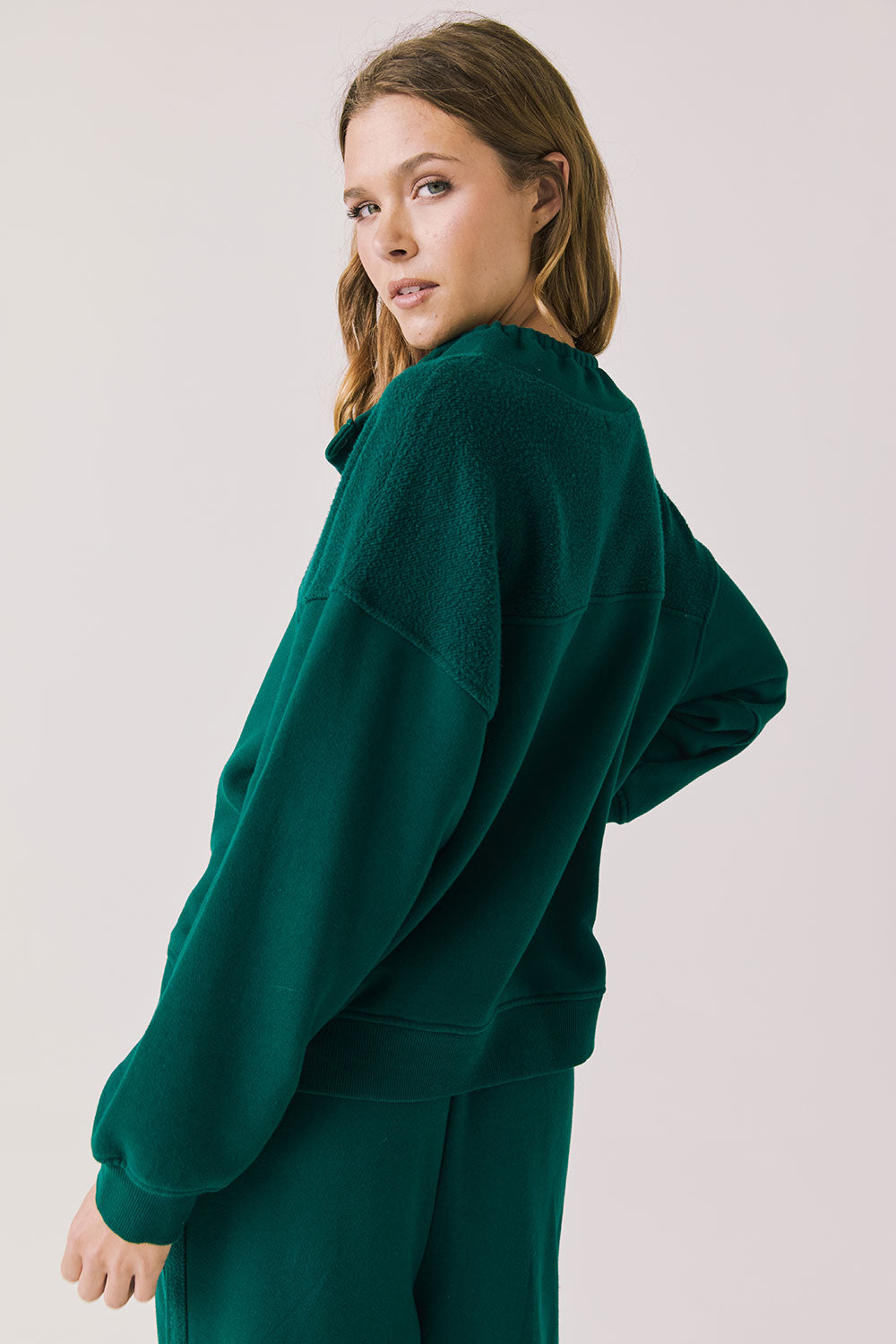 Back view of woman wearing Chaser’s City Blue Grass Green Half Zip Pullover with white drawstrings on a plain background