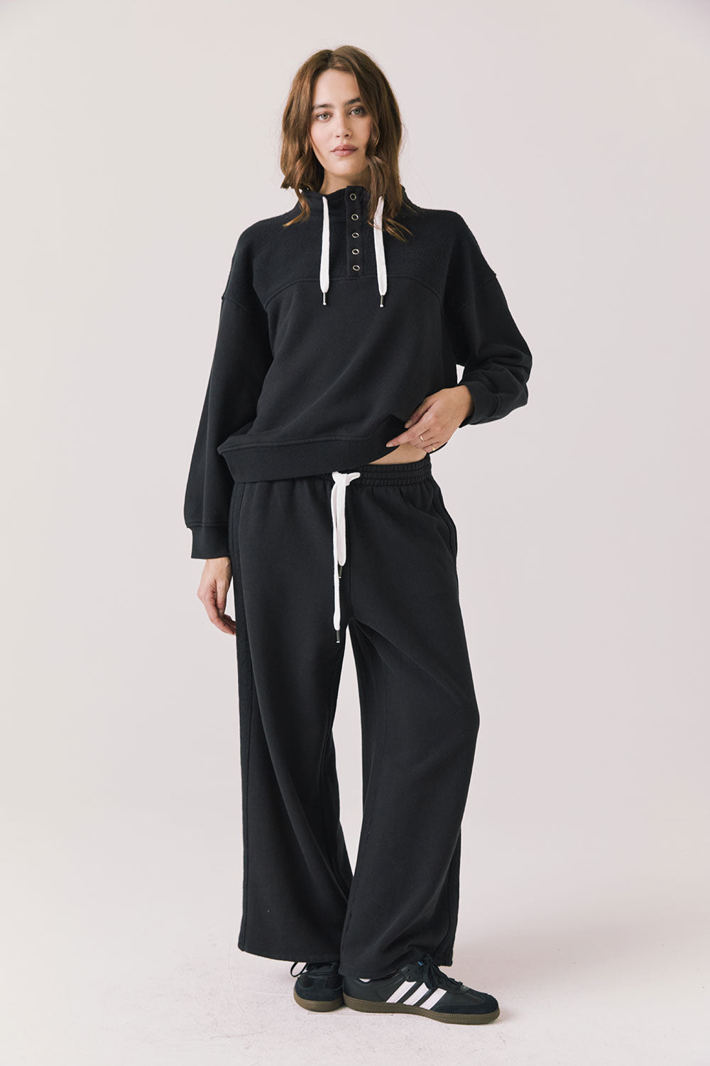 Full body view of woman wearing Chaser’s City True Black Half Zip Pullover with matching Hazel Joggers on a plain background