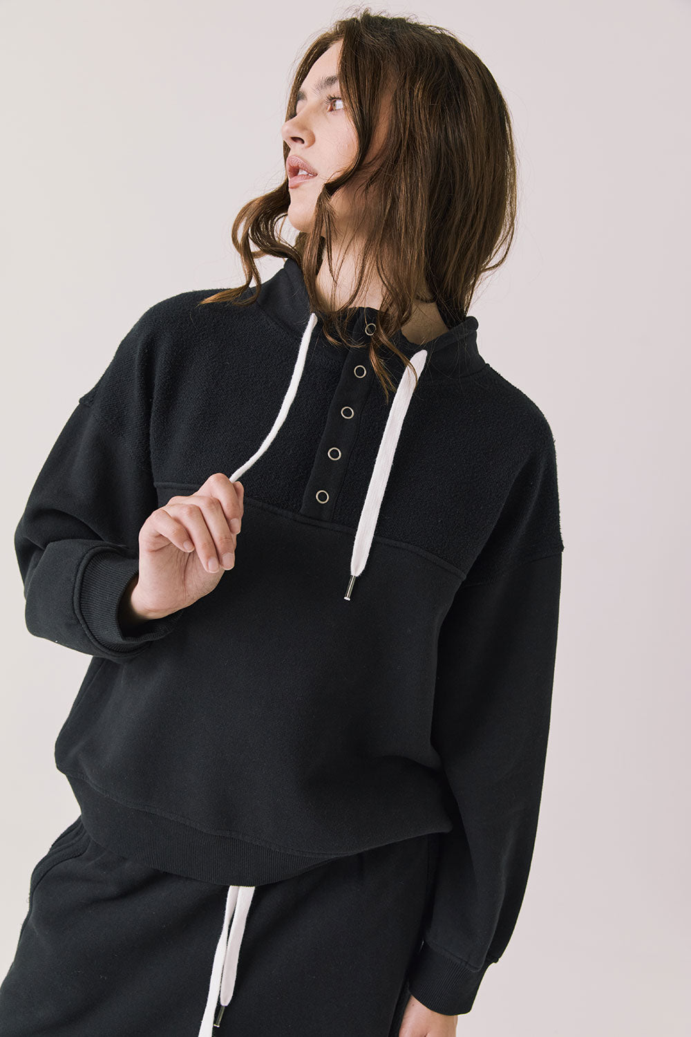 Front view of woman wearing Chaser’s City True Black Half Zip Pullover with white drawstrings on a plain background