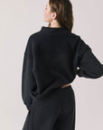 Back view of woman wearing Chaser’s City True Black Half Zip Pullover with white drawstrings on a plain background