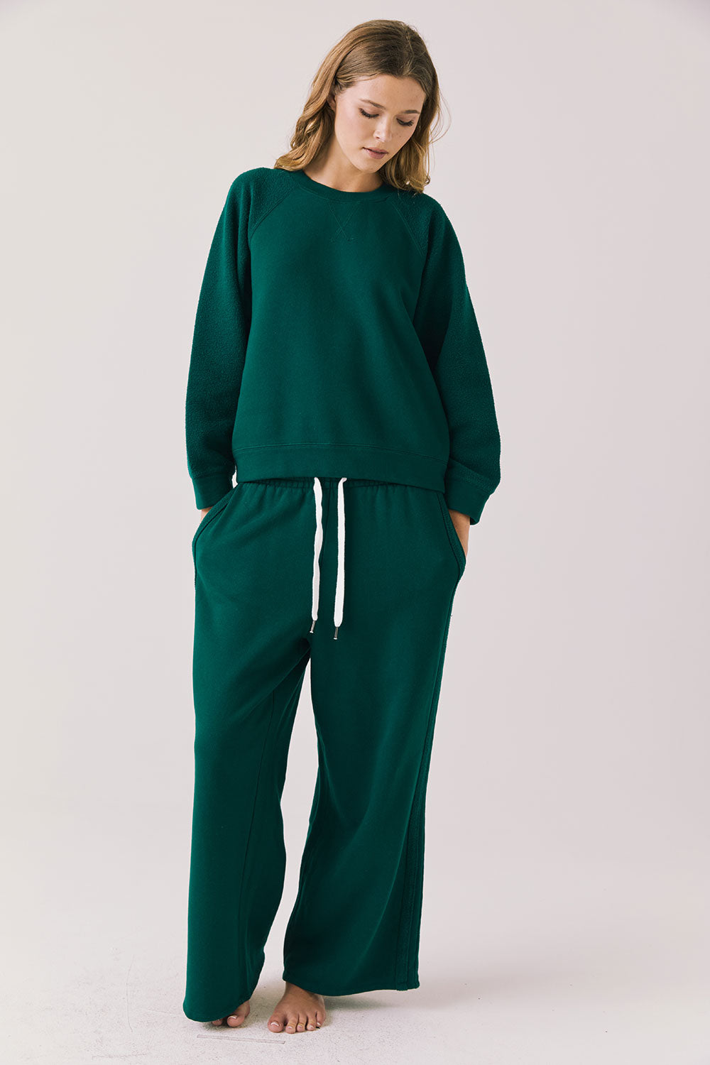 Full body view of woman wearing Chaser’s Cello Blue Grass Green Pullover with matching Hazel Joggers on a white background