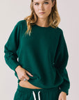 Front view of woman wearing Chaser’s Cello Blue Grass Green Pullover on a white background