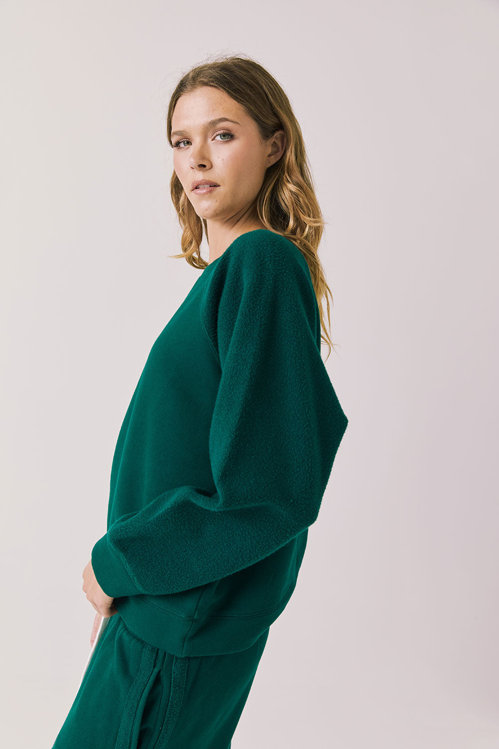 Side view of woman wearing Chaser’s Cello Blue Grass Green Pullover on a white background