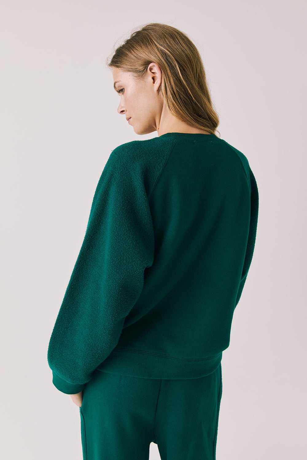 Back view of woman wearing Chaser’s Cello Blue Grass Green Pullover on a white background