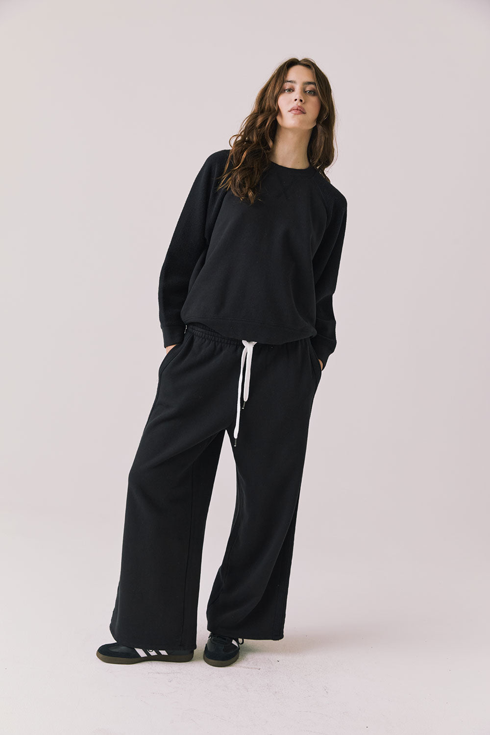 Full body view of woman wearing Chaser’s Hazel True Black Joggers with matching Cello True Black Pullover on a white background