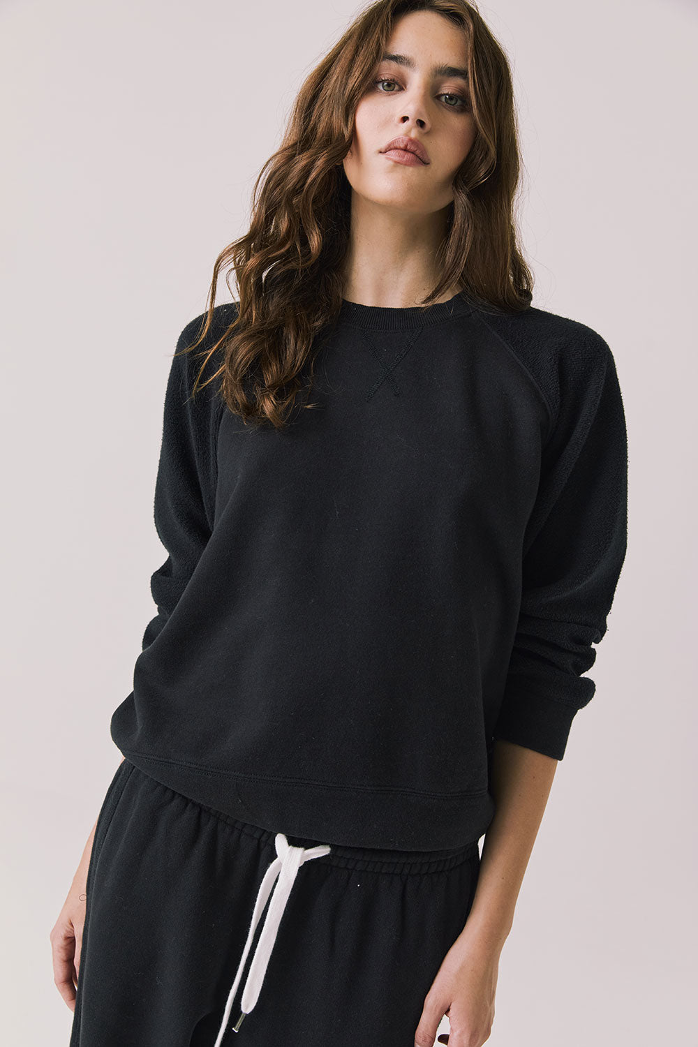 Front view of woman wearing Chaser’s Hazel Joggers in true black on a white background