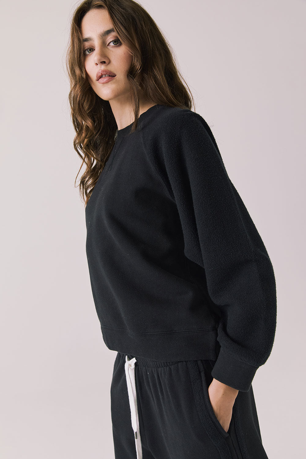 Side view of woman wearing Chaser’s Cello True Black Pullover on a white background
