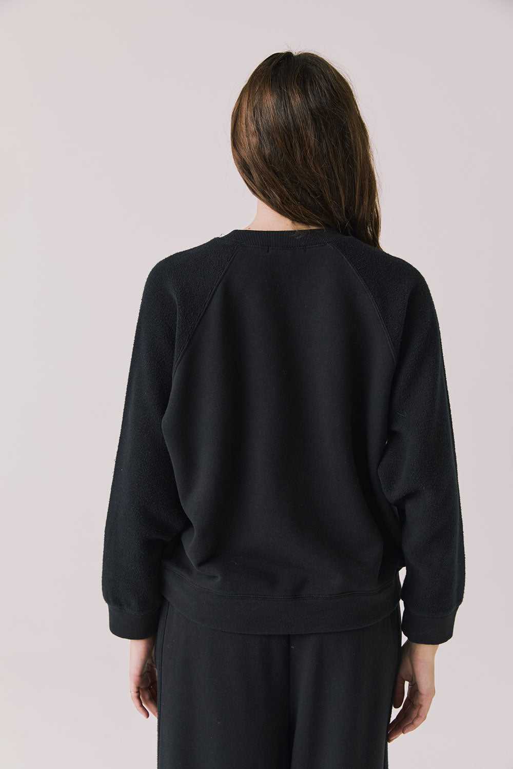 Back view of woman wearing Chaser’s Cello True Black Pullover on a white background