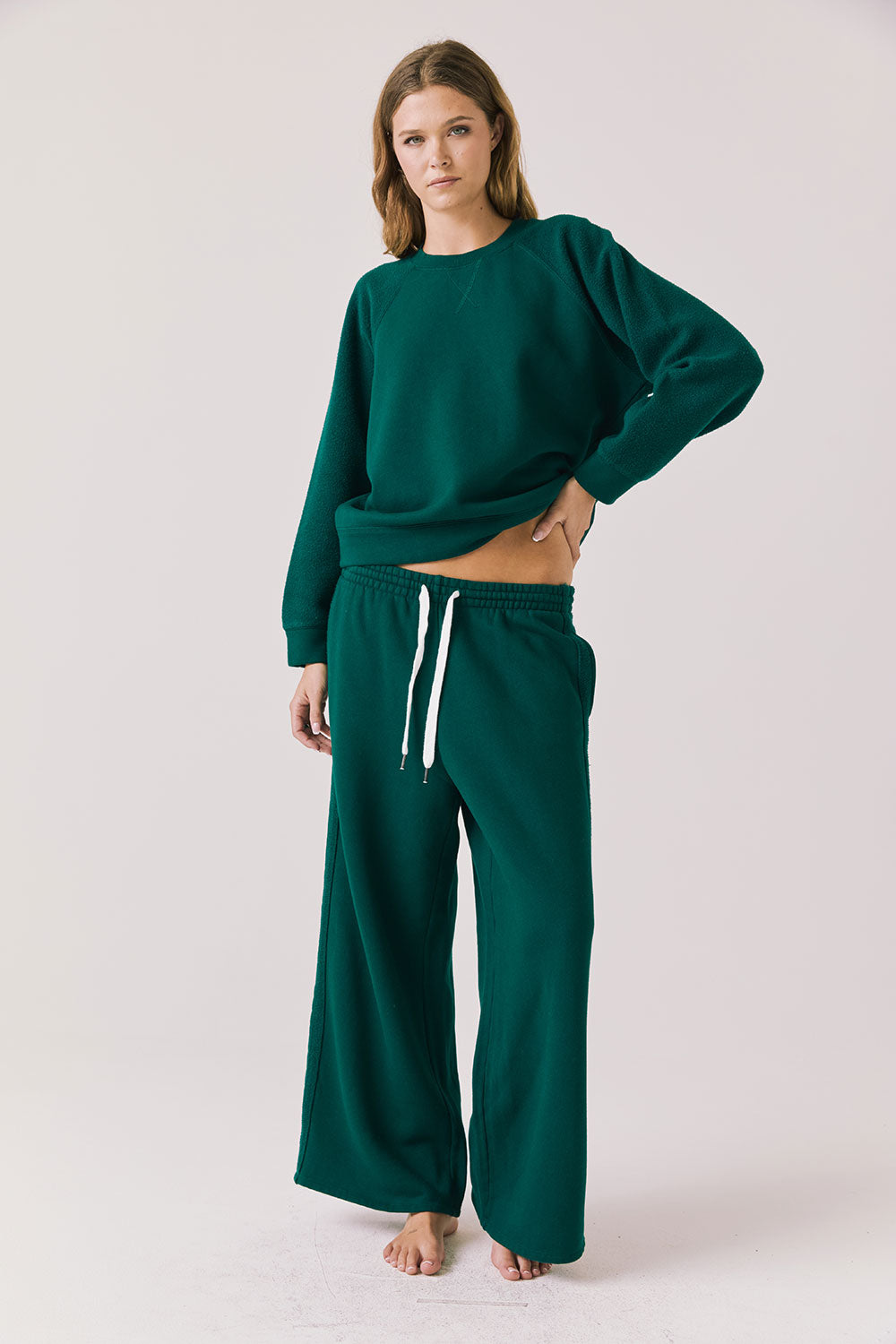 Full body view of woman wearing Chaser’s Hazel Joggers in Blue Grass Green with matching Cello Blue Grass Green Pullover on a white background