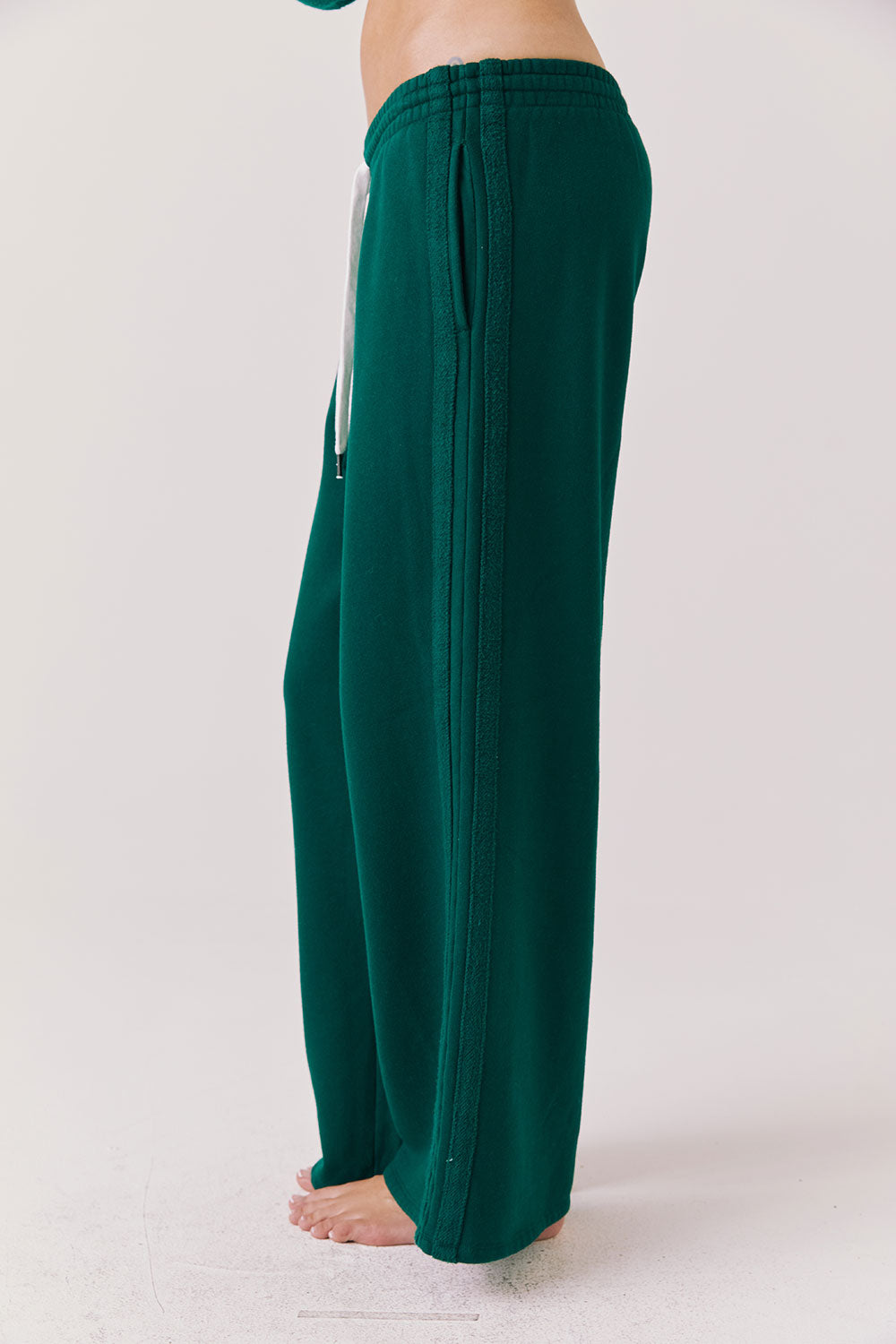 Side view of woman wearing Chaser’s Hazel Joggers in Blue Grass Green on a white background