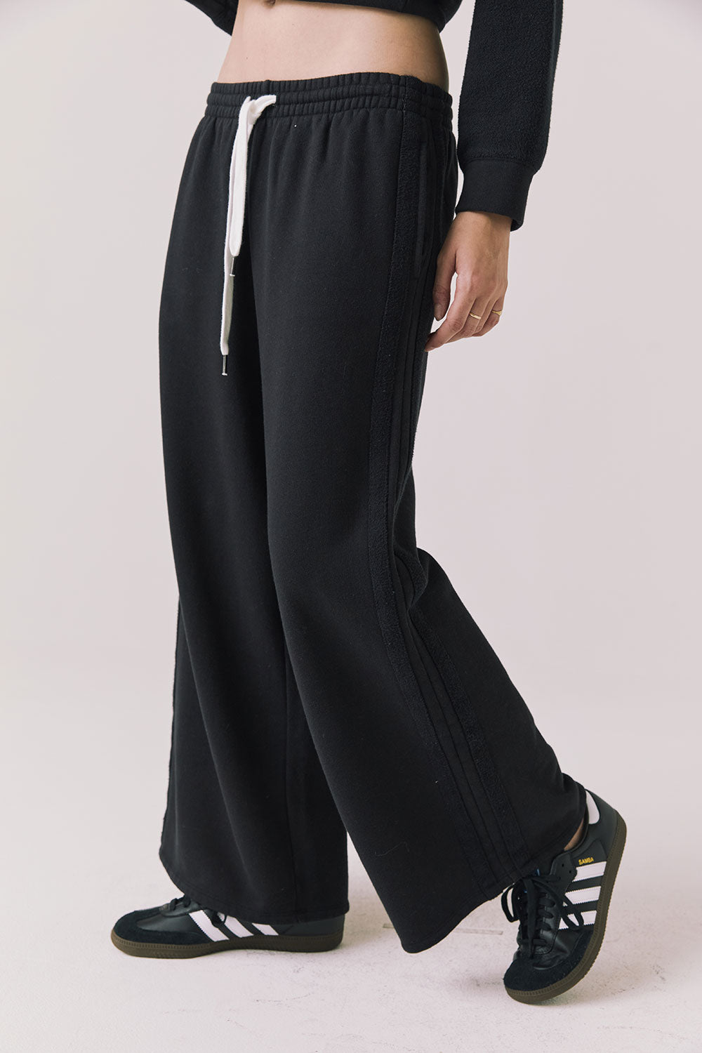 Side view of woman wearing Chaser’s Hazel Joggers in true black on a white background