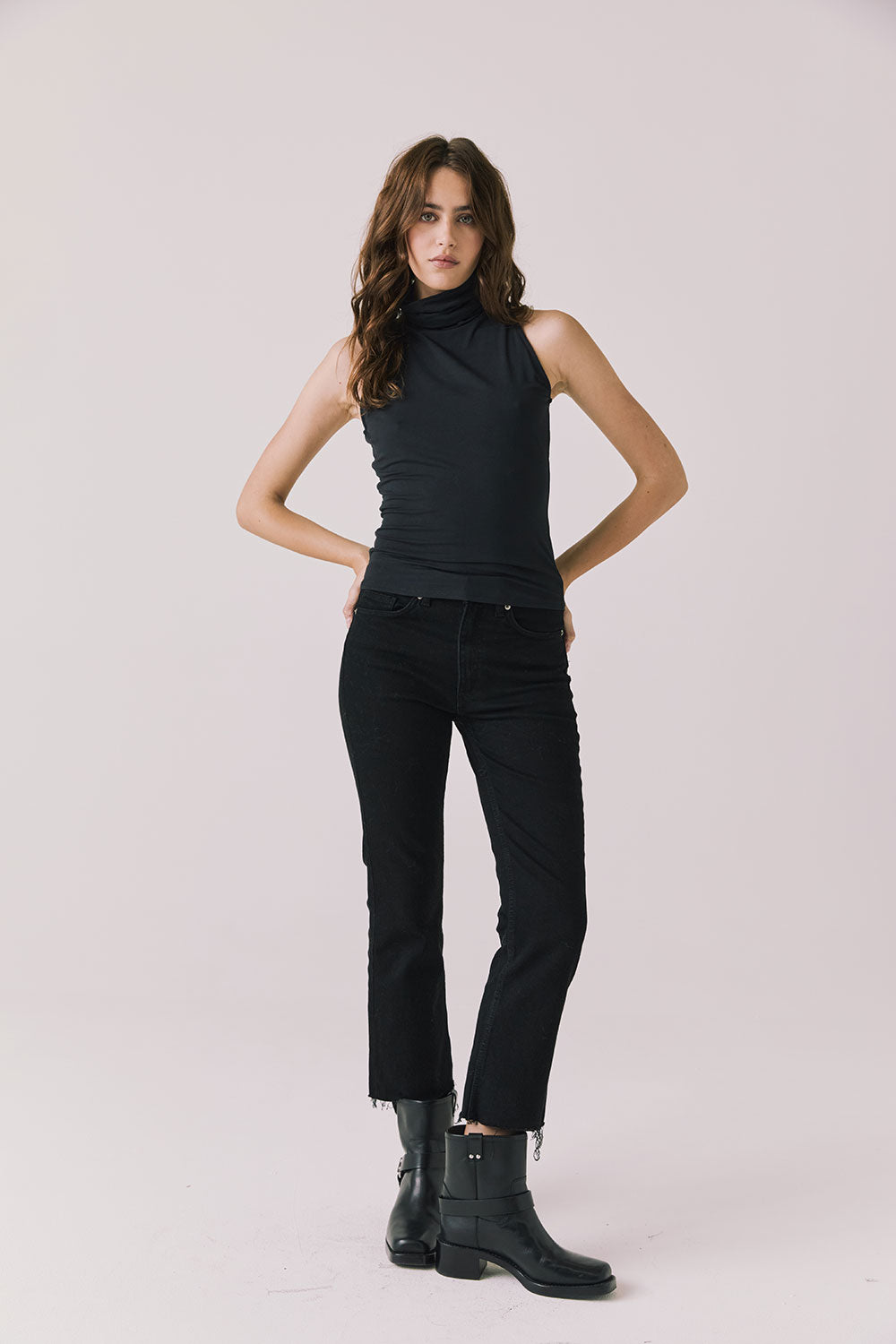 Full body view of woman wearing Chaser’s Hailee Black Tank with black pants and boots on a white background