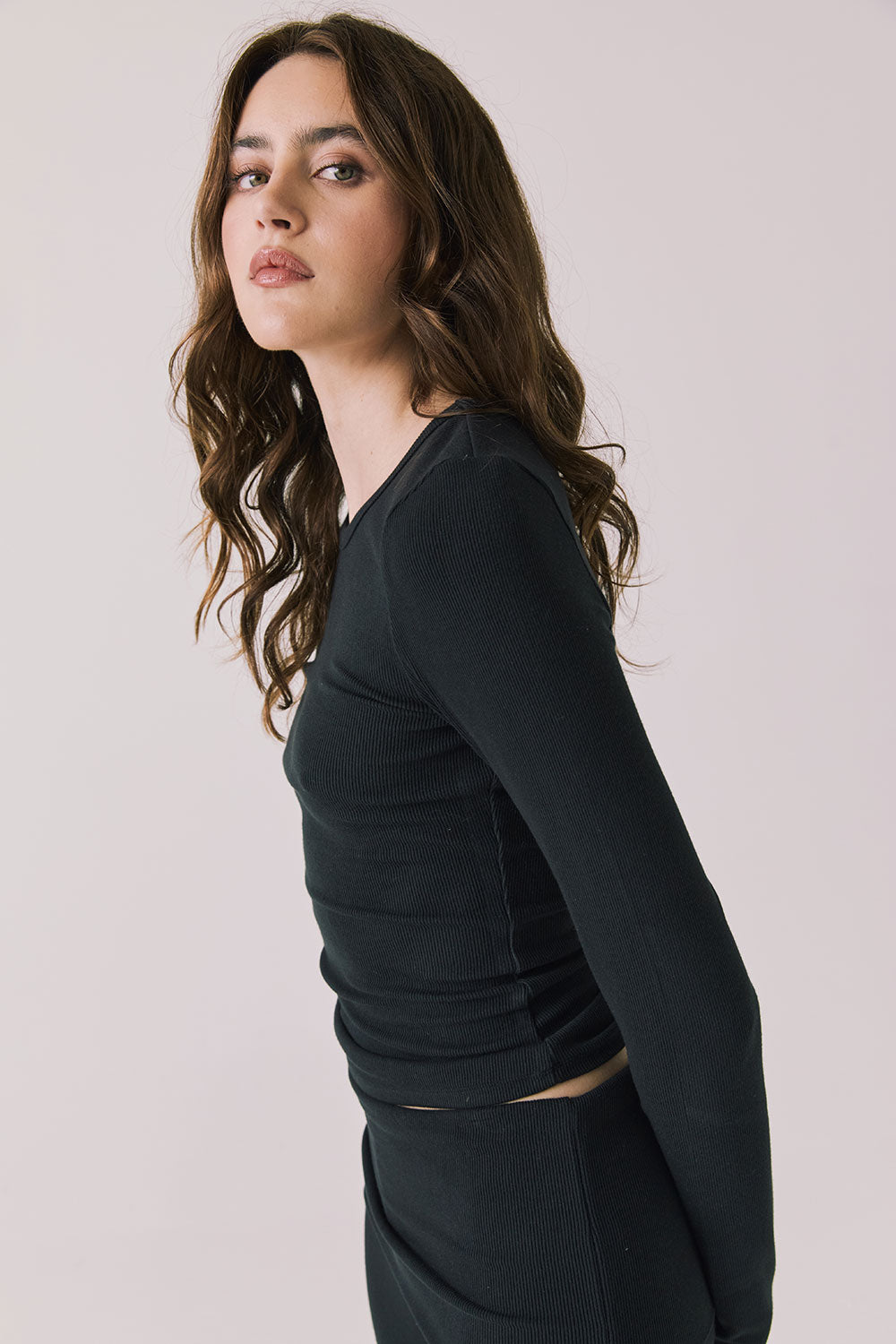 Side view of woman wearing Chaser’s Porta True Black Long Sleeve top showing relaxed fit on a white background