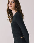 Side view of woman wearing Chaser’s Porta True Black Long Sleeve top showing relaxed fit on a white background