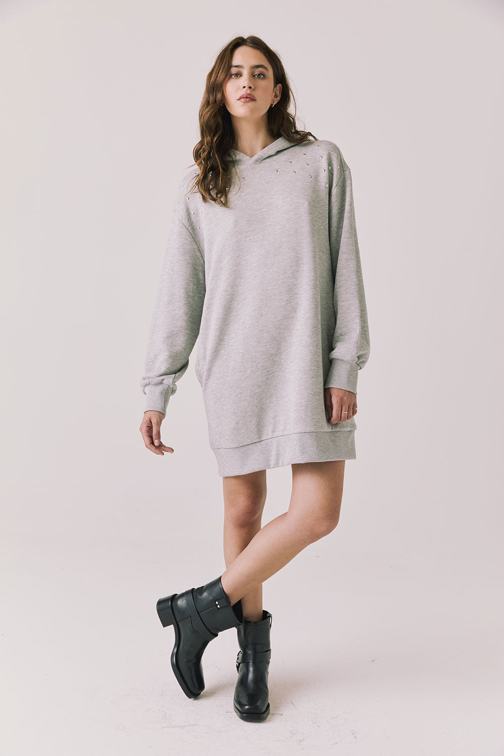 Woman wearing Chaser's Aster Heather Grey Hoodie Dress with black boots on a plain background