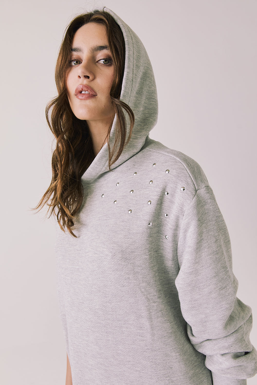 Woman wearing Chaser's Aster Heather Grey Hoodie Dress with hoodie up on a plain background