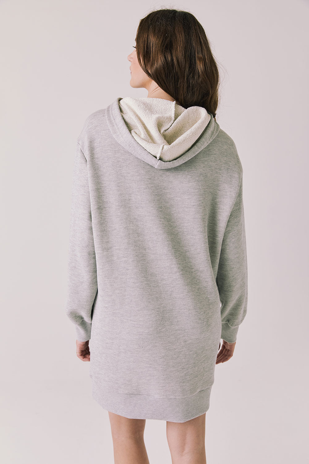 Back view of woman wearing Chaser's Aster Heather Grey Hoodie Dress on a plain background