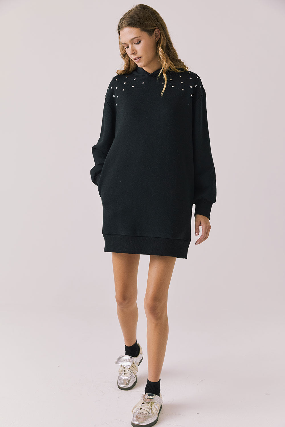 Woman wearing Chaser Aster True Black Hoodie Dress with decorative elements on shoulders on a plain background
