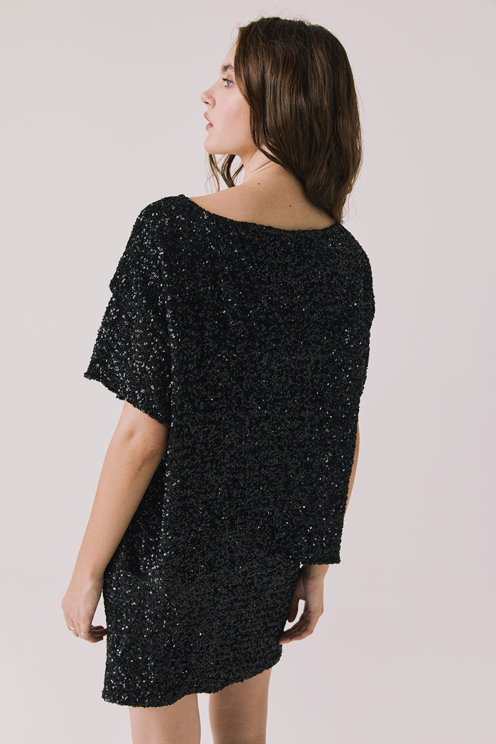Back view of woman wearing Chaser’s Jayde True Black Mini Skirt with matching Davis True Black Tee on a light gray background