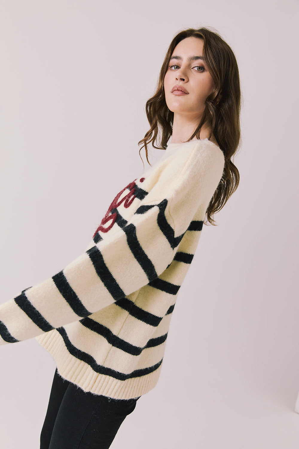 Side view of woman wearing Chaser’s striped Merci Long Sleeve Sweater with “merci” burgundy red text on a white background