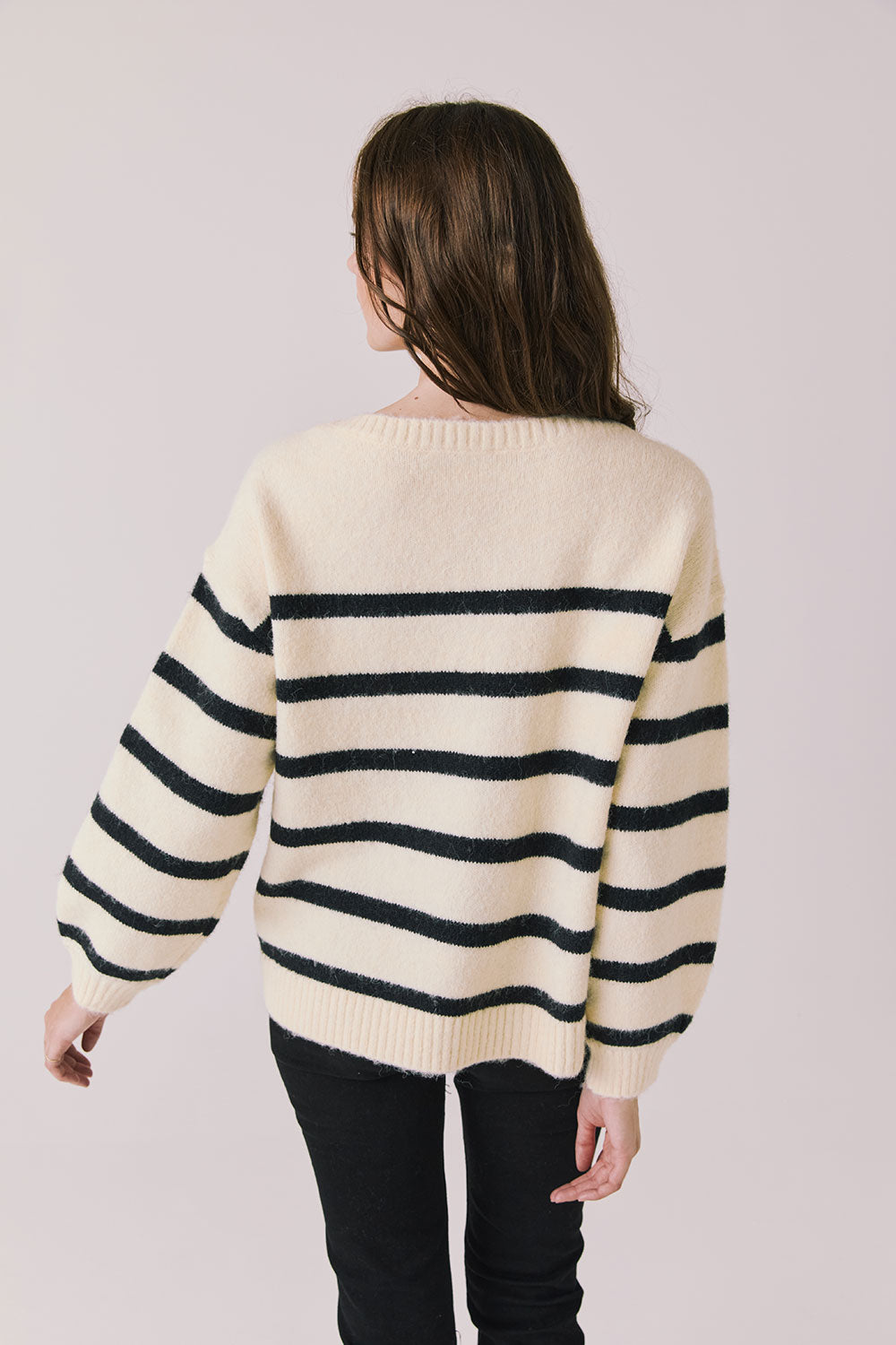 Back view of woman wearing Chaser’s striped Merci Long Sleeve Sweater on a white background