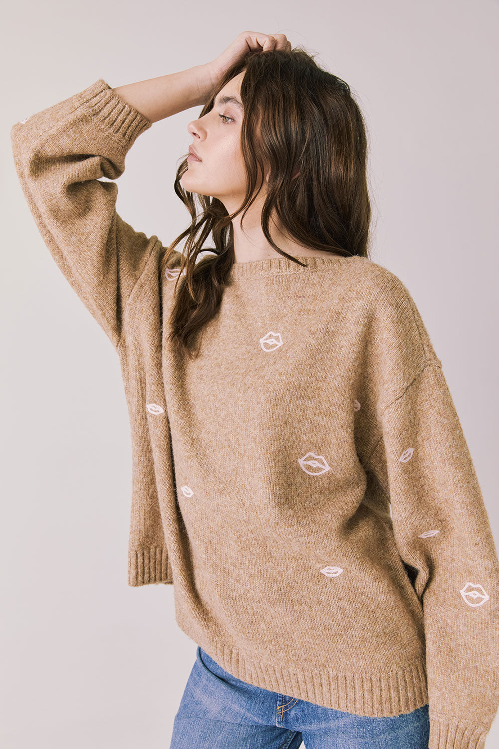 Side view of woman wearing Chaser’s Love Me Long Sleeve Beige Sweater on a plain background