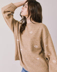 Side view of woman wearing Chaser’s Love Me Long Sleeve Beige Sweater on a plain background