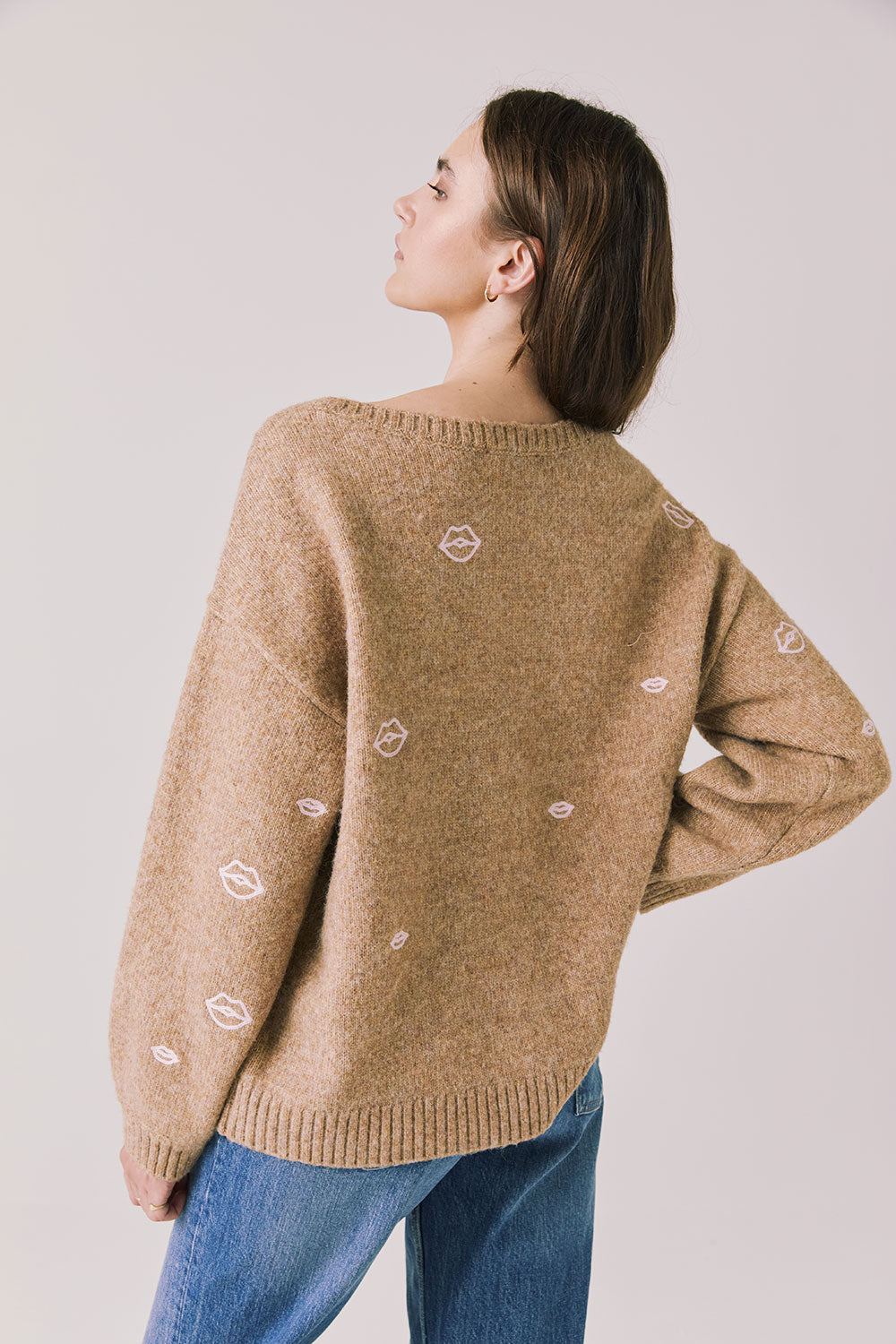 Back view of woman wearing Chaser’s Love Me Long Sleeve Beige Sweater on a plain background