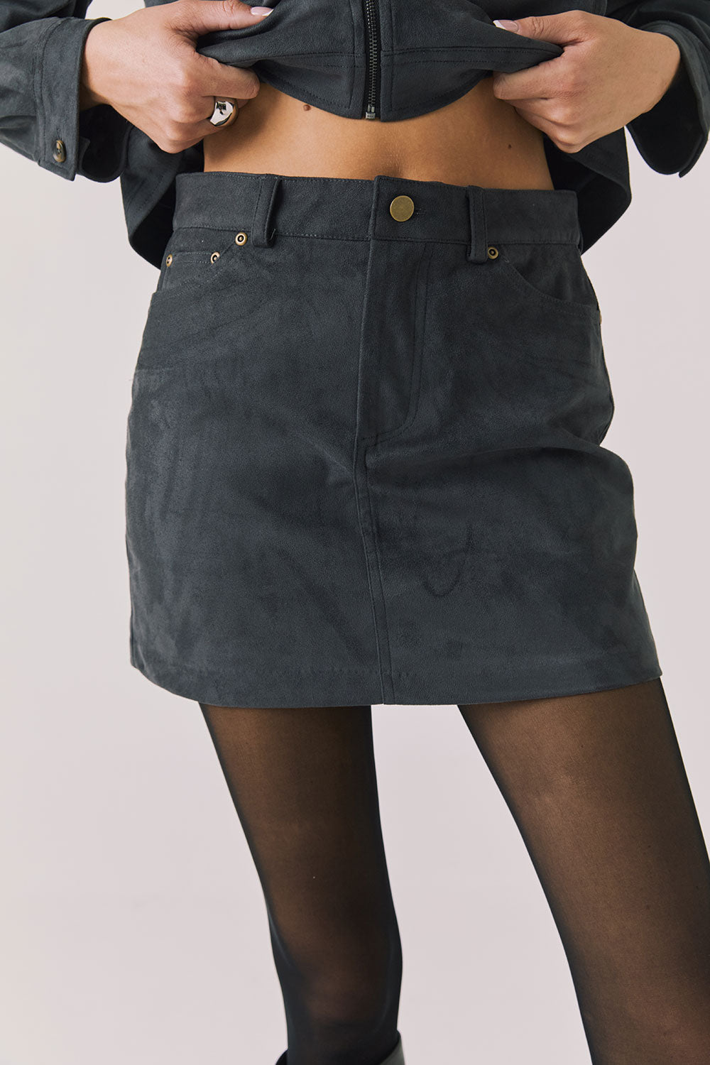 Front view of woman wearing Chaser’s Brooke True Black Mini Skirt on a light background