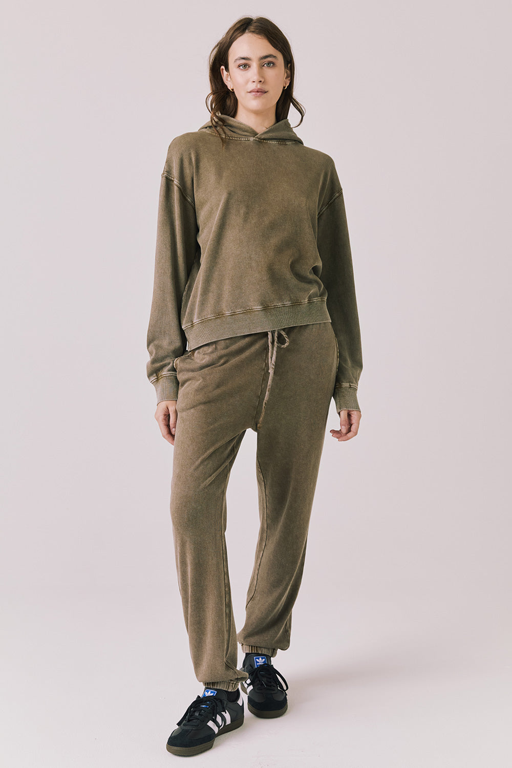 Full body view of woman wearing Chaser’s Ginger Brown Martini Pullover Hoodie with matching Manhattan Joggers on a light pink background