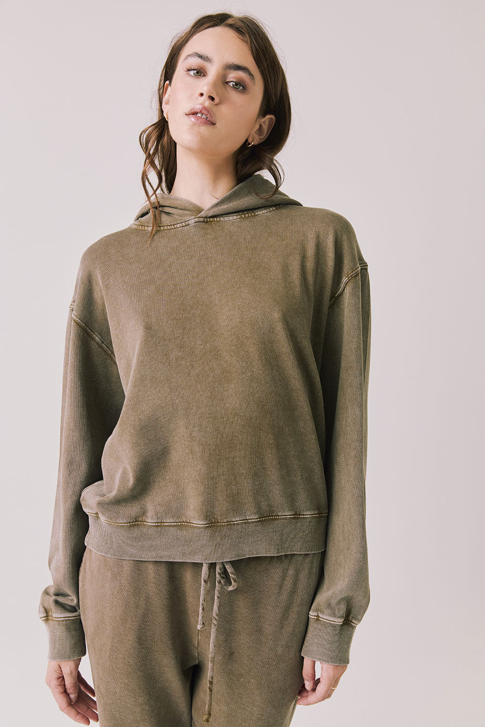 Front view of woman wearing Chaser’s Ginger Brown Martini Pullover Hoodie on a light pink background