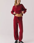 Full body view of woman wearing Chaser’s Monica Purple-Red Fig Joggers with matching Miller Purple-Red Fig Pullover Sweater on a white background
