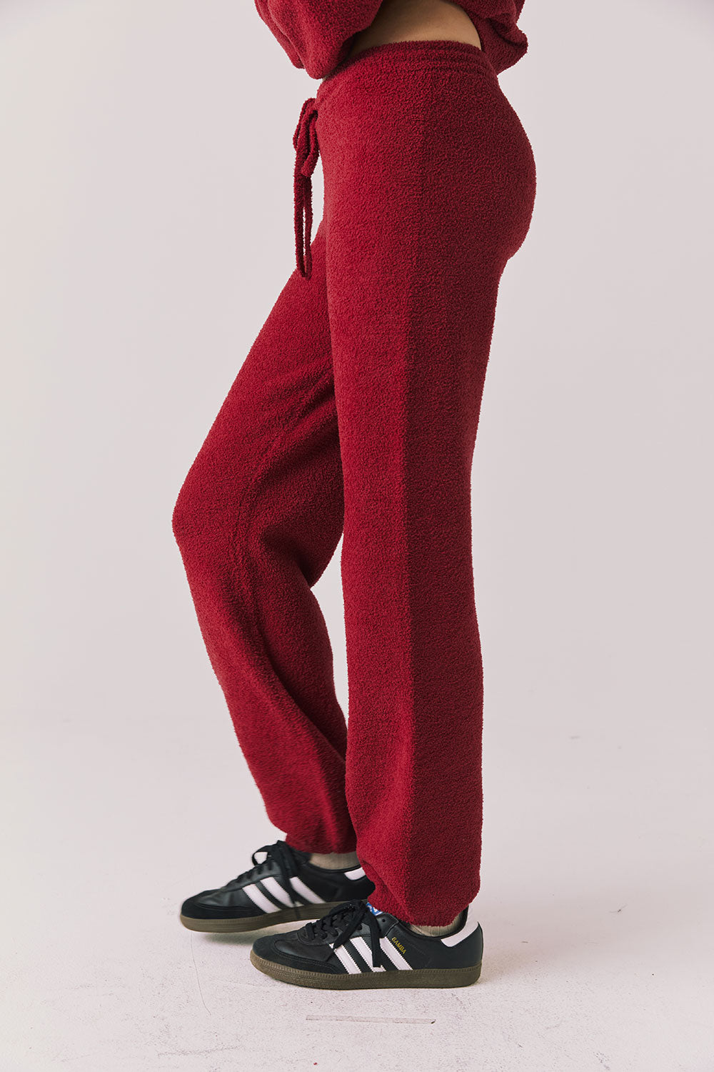 Side view of woman wearing Chaser’s Monica Purple-Red Fig Joggers on a white background