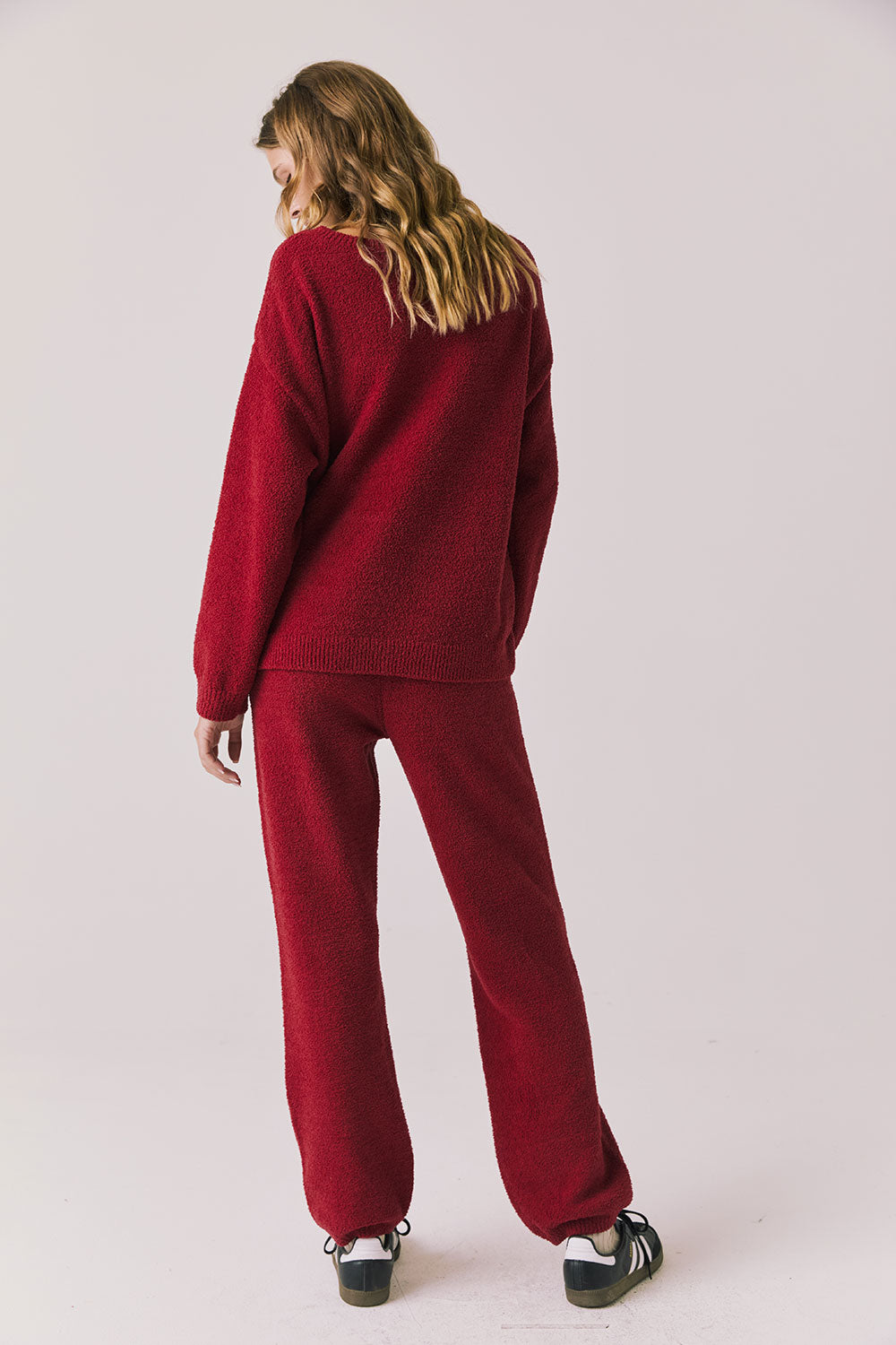 Full body back view of woman wearing Chaser’s Monica Purple-Red Fig Joggers with matching Miller Purple-Red Fig Pullover Sweater on a white background