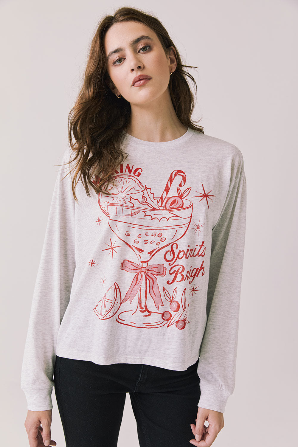 Front view of woman wearing Chaser’s Spirits Bright Light Grey Long Sleeve with red graphics and text on a light gray background