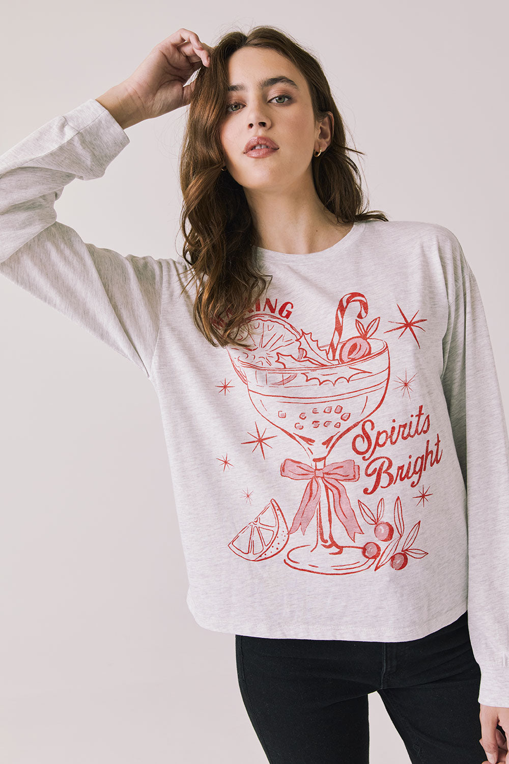Front view of woman wearing Chaser’s Spirits Bright Light Grey Long Sleeve with red graphics and text on a light gray background