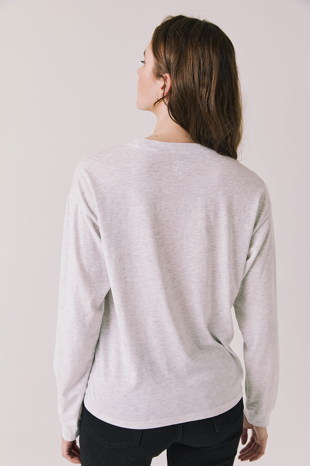 Back view of woman wearing Chaser’s Spirits Bright Light Grey Long Sleeve on a light gray background