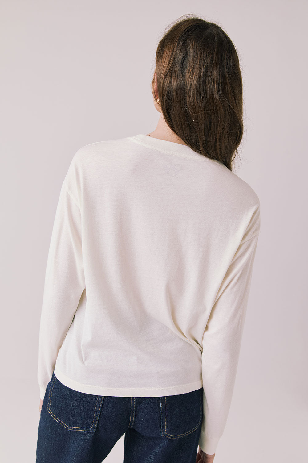 Back view of woman wearing Chaser’s starry white Willie Nelson Luck Texas Long Sleeve on a light background (licensed band collaboration)