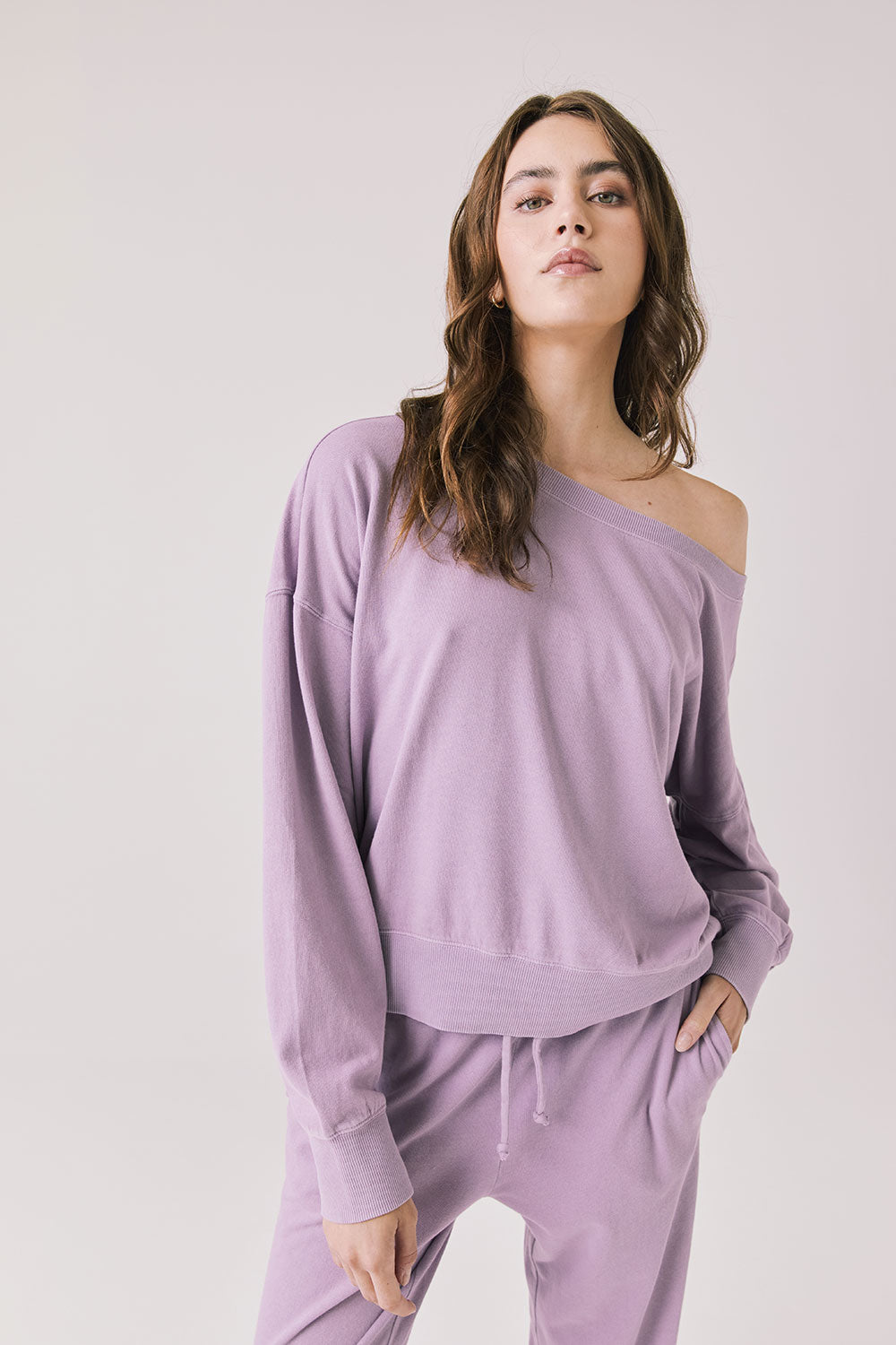 Woman wearing Chaser's Bellini Amethyst Purple Pullover with matching pants on a plain background