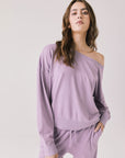Woman wearing Chaser's Bellini Amethyst Purple Pullover with matching pants on a plain background