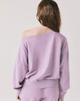 Back view of woman wearing Chaser's Bellini Amethyst Purple Pullover with matching pants on a plain background
