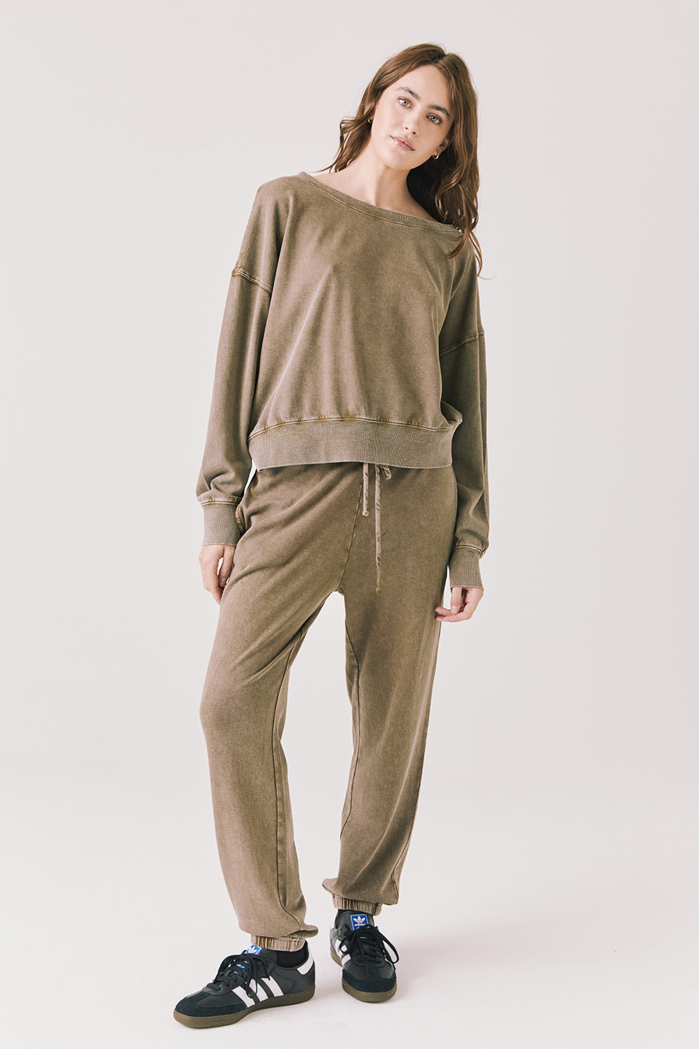 Woman wearing Chaser's Bellini Ginger Brown Pullover and matching Manhattan joggers with black sneakers on a white background