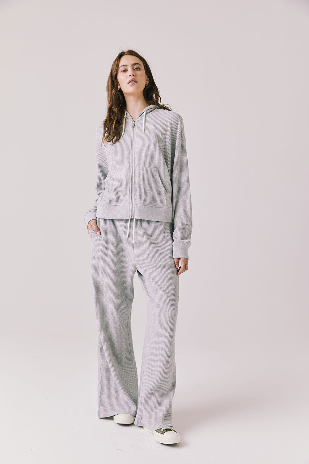 Woman wearing the Abilene Light Heather Grey Zip Up Hoodie with matching pants on a white background