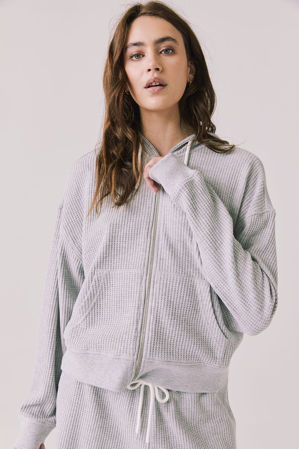 Woman wearing the Abilene Light Heather Grey Zip Up Hoodie with matching pants on a white background