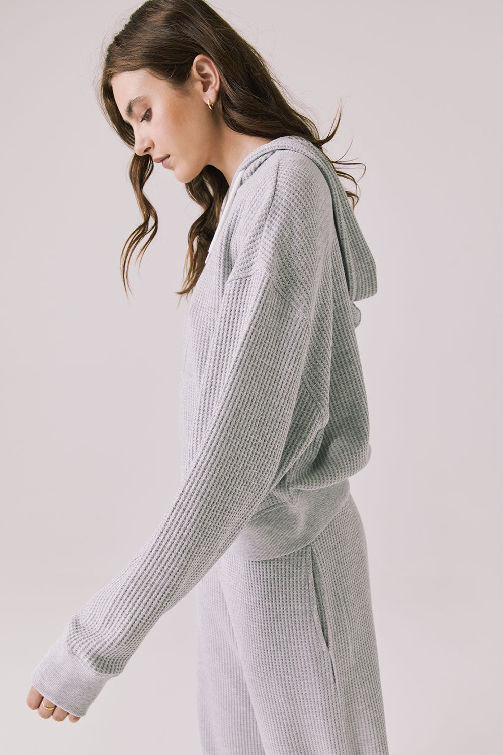 Side view of wearing the Abilene Light Heather Grey Zip Up Hoodie with matching pants on a white background