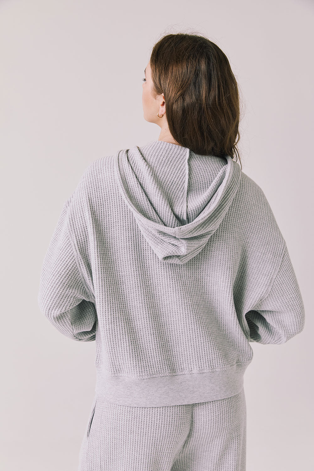 Back view of woman wearing the Abilene Light Heather Grey Zip Up Hoodie with matching pants on a white background